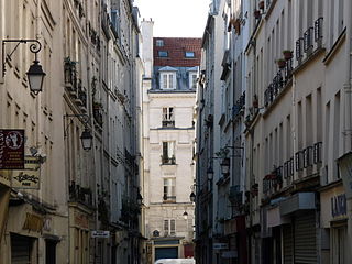 (ランビュトー通りの北側を東西に並走する)シャポン通りを、(同通りと南北に交差する)ボーブール通りから(同様に南北に交差する)サン＝マルタン通り方向西側を見る (Rue Chapon, vue vers l'ouest, prise de la Rue Beaubourg.)。画像はシャポン小 (École primaire Chapon) があるボーブールとの交差点側から撮影。。