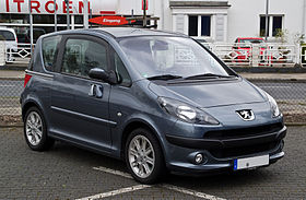 Front-three-quarter view of a three-door car with sliding passenger doors and front fog lamps