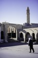 A round gate, the entrance to the carpet market. "Shop Berber". A satellite dish. A tower of a mosque, Tozeur, 1997.