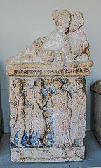 Sculpture en pierre d'un couple enlacé, sous lequel apparaissent quatre personnages en bas-relief.