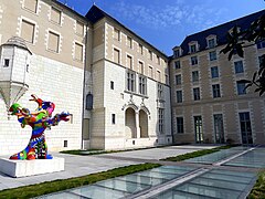 Photographie d'une cour d'un logis Renaissance, œuvre de Nikki de Saint Phalle au premier plan.