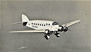 Photographie en noir et blanc d'un avion à hélice en vol.