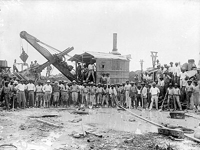 Bauxietwinning in Moengo. Werknemers poseren voor een stoomgraafmachine in een bauxietgroeve (ca.1930)