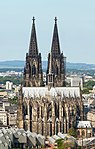 A large, brightly lit cathedral sits in the middle of a skyline at night.