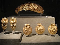 Exposition d'une couronne en or imitant des feuilles, avec 5 autres bijoux ronds en or, finement gravés et sculptés.