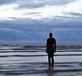 fera skulptaĵo "alia loko" de la artisto Antony Gormley en la plaĝo Crosby Beach de la Irlanda maro apud Liverpool
