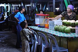 Niño comprando 'agua de coco' en un mercado de Kota Kinabalu