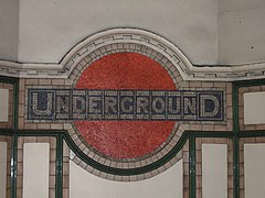 De underground roundel als mozaïek boven de trap in de stationshal.