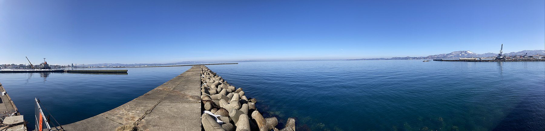 Panorama of Aomori Bay as it is seen from the mouth of the Tsutsumi River with central Aomori to the far-left, Tsugaru Peninsula at center-left, and Natsudomari Peninsula to the right.