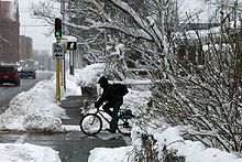 Cyclist waiting at a stoplight in the snow.