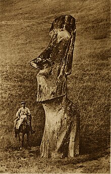 De gauche à droite, un cavalier chilien faisant 1/4 de la taille de la statue moai représentant un visage géant.