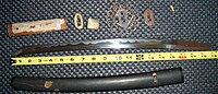 An antique Japanese wakizashi with koshirae and related parts, shown dis-assembled. The hamon (temper line) is clearly visible.