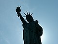 Profile Statue of Liberty in front of the sun.