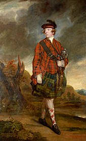 A man wearing a black hat, a red plaid shirt and socks, a green plaid kilt, and black shoes with gold buckles, carrying a satchel with its strap across his chest