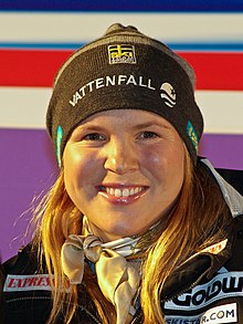 Anja Parson, close in on her face, as she smiles. She is wearing a black ski hat.