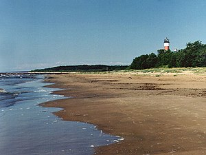 Narva-Jõesuus sandstrand 1998. Bilden är tagen österut i sandstrandens östra del där man ser fyren. Bakom fyren mynnar floden Narva ut (syns ej i bilden). Skogspartiet som ligger längst bort i bilden ligger i Ryssland.