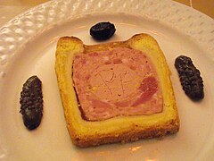 Pâté en croûte de type Richelieu, accompagné de deux moitiés de cornichon et d'une olive noire.