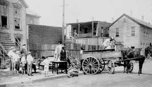 An African-American family moves furniture out of a house with broken windows.