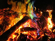 Fotografía de llamas de colores rojo, magenta, amarillo, azul y verde que se desprenden de la quema o combustión de trozos de cobre.