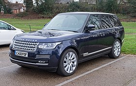 A blue Range Rover Sentinel parked stationary on a cobbled street in front of a white building.