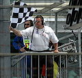 A marshal at the Menards Infiniti Pro Series support race waving a checkered flag