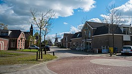 Gezicht op de Methardusstraat met linksachter de gereformeerde kerk, rechtsachter de korenmolen en rechtsvoor café De Sluys