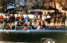 John F. Kennedy ngồi trên limousine, vẫy tay chào đám đông ở Elm Street, Dealey Plaza.