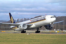 Aircraft takeoff. Front quarter view of jet lifting off, with wings flexed upwards, condensation in the engines, and the aft landing gear still touching the runway.