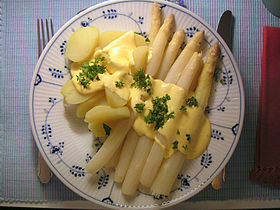 Boiled, peeled and sliced potato with white asparagus served with sauce hollandaise and sprinkled with parsley