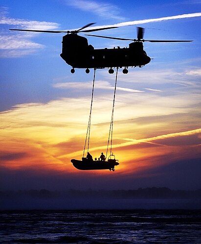 Вертолёт «Чинук» Королевских военно-воздушных сил транспортирует на внешней подвеске надувную лодку морской пехоты у побережья Дорсета в Англии