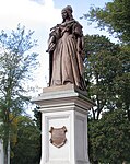 Staty föreställande Lovisa Henrietta av Oranien-Nassau. I bakgrunden slottsparken.