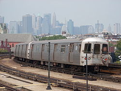 A New York-i metró egyik szerelvénye, a háttérben New York felhőkarcolói