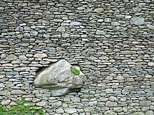 Mur de maçoneria de pedra en sec engolint una gran roca a Lakes, Anglaterra