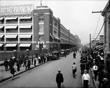 Masses of men throng the streets outside a building.