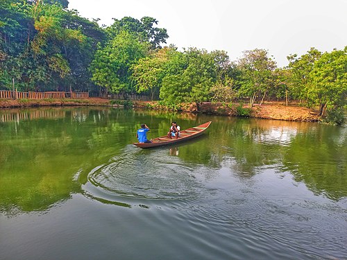 In this photo, are two men sitting in a canoe and having a conversation as they paddle the canoe on the green waters. Photograph: User:Aud Content