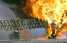 Firefighters fight to secure a burning oil well in the Iraqi Rumaila oilfields in 2003.[28]