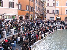 Une foule de personnes agglutinée au bord d’un bassin.