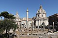 Restes de la Basílica Úlpia amb la Columna de Trajà al darrere; al fons, l'església barroca del Sagrat Nom de Maria