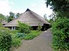 Hallenhuisboerderij met voorhuis tegen puntgevel onder rieten zadeldak, stal onder hoog rieten zadeldak en bakhuis