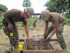 US Navy 100825-N-5390M-032 Steelworker 3rd Class Henry O'Hair, left, and Steelworker Anthony Thompson, both assigned to Amphibious Construction Battalion (ACB) 1 based in San Diego, lower a reinforcing steel cage into a ground.jpg