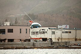 Ein auf ein Tankstellendach im Hafen von Ōfunato angespültes Segelboot (Foto: 21. März 2011)