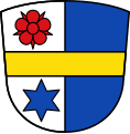 Gemeinde Wollmetshofen Gespalten von Silber und Blau, belegt mit einem durchgehenden goldenen Balken; vorne oben schwebend eine rote Rose, vorne unten ein sechsstrahliger blauer Stern.