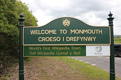 La foto del cartello di benvenuto a Monmouth che mostra come entrando nel paese si entri anche in Wikipedia.