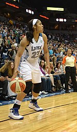 full height portrait of a young woman with long dark hair pulled back, wearing uniform that says "Lynx 23"