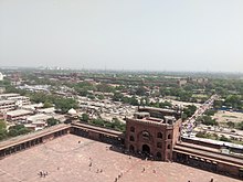 La imagen muestra las largas murallas del Fuerte Rojo, incluidas las puertas, vistas desde la torre de Jama Masjid. Las murallas pueden verse al fondo extendiéndose un par de miles de metros.