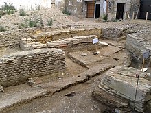 Photographie d'un site de fouilles. Quelques murs sont visibles.