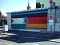 Le bandiere sul Muro di Berlino (East Side Gallery), per esprimere la solidarietà delle nazioni e delle religioni vicino a Oberbaumbrücke lo sfondo di Pittura dal titolo "Patria" di Gunther Schaefer.