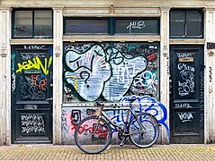 Parked bicycle with graffitied building facade and doors in Amsterdam.jpg