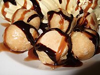 Profiteroles with chocolate and caramel sauces drizzled on them