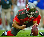 Kneeling to hold a football for the kicker